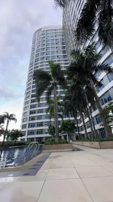 a tall building with palm trees in front of it at New Cozy Condo in Eastwood in Manila