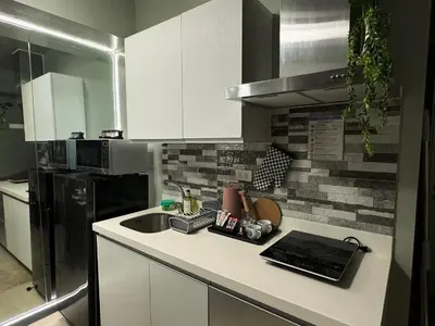 a kitchen with white cabinets and a sink and a refrigerator at Oasis City Ventures in Manila