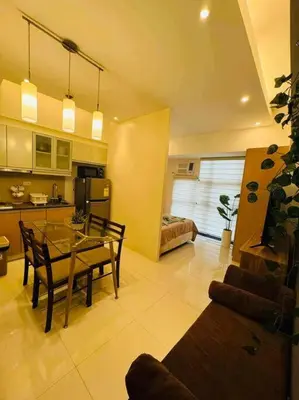 a kitchen and living room with a table and chairs at Staycation in Mckinley walking distance to Venice Mall in Manila