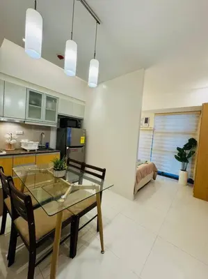 a kitchen with a glass table and chairs in a room at Staycation in Mckinley walking distance to Venice Mall in Manila