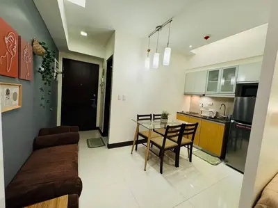 a kitchen and a living room with a table and chairs at Staycation in Mckinley walking distance to Venice Mall in Manila