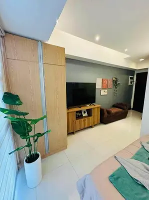 a living room with a couch and a television at Staycation in Mckinley walking distance to Venice Mall in Manila