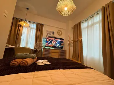a bedroom with a large bed with a tv in it at Budget Friendly Staycation walking distance to Venice Mall with Netflix and Wifi in Manila