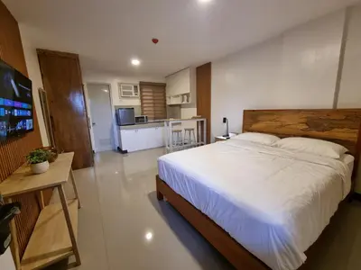 a bedroom with a large bed and a kitchen at Flat 35, Unit F in Manila