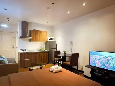 a living room with a table and a kitchen at Spacious Unit in Gramercy Makati in Manila