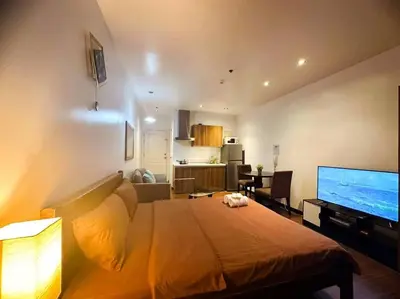 a bedroom with a bed and a living room with a television at Spacious Unit in Gramercy Makati in Manila