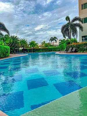 a swimming pool with blue water and palm trees at Natural Haven at South in Manila