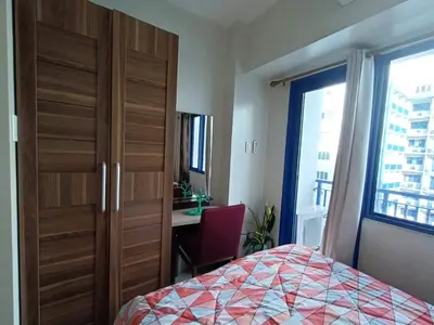 a bedroom with a bed and a desk and a window at Jericho's Place in Manila