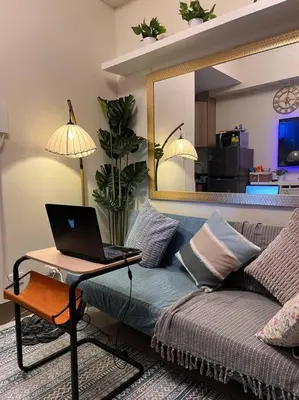 a living room with a couch with a laptop on a table at Cozy Vibrant Staycation Netflix Wifi Mandaluyong in Manila