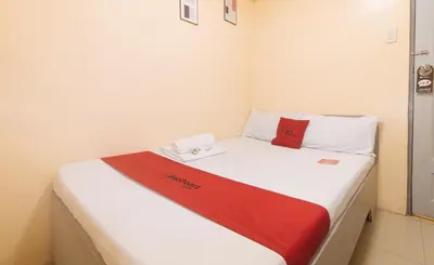 a bed with a red and white blanket on it at RedDoorz at LYOTO Bed and Breakfast near NAIA Terminal in Manila