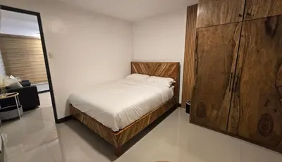 a bedroom with a bed and a large wooden cabinet at Flat 35, Unit D in Manila