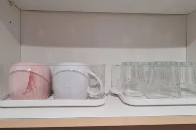 two cups and glasses are sitting inside of a refrigerator at 1BR with Balcony Condo accross NAIA T3 in Manila