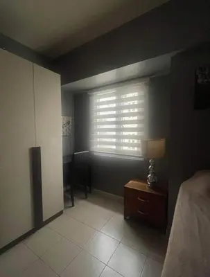 a bedroom with a window with a lamp and a table at Avida San lorenzo Tower 1 in Manila