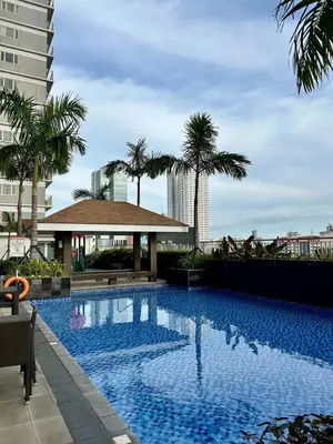 a large swimming pool with palm trees and a building at City Serenity Escape in Manila