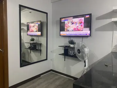 a room with a mirror and a fan on a wall at Tiaras Luxury Condotel in Manila