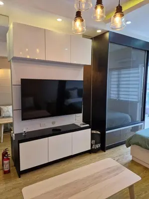 a living room with a large flat screen tv at Cozy retreat w Balcony, Netflix, 100 mbps internet, Pool, near BGC in Manila