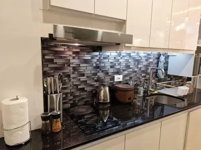 a kitchen with a black counter top with a sink at Cozy retreat w Balcony, Netflix, 100 mbps internet, Pool, near BGC in Manila