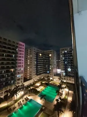 a view of a pool in a city at night at Sea Residences by Richnell's Staycation 