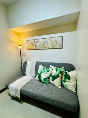 a couch with pillows on it in a room at 10G Cozy Condo at Park McKinley West near Venice Mall in Manila