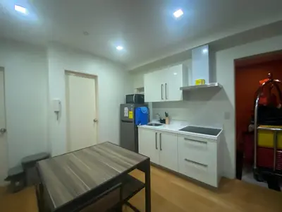 a kitchen with white cabinets and a wooden table at The Home Ikigai in Manila