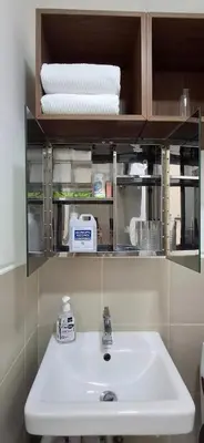 a bathroom with a sink and a shelf with towels at Hideouts & Hangouts in Manila