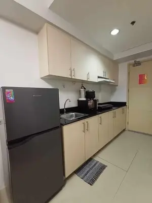 a kitchen with a black refrigerator and a sink at Sea Residences Karen's Staycation in Manila
