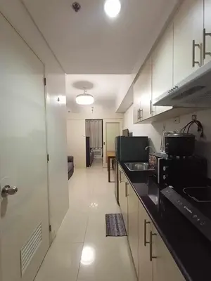 a kitchen with white cabinets and black counter tops at Sea Residences Karen's Staycation in Manila