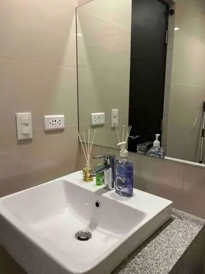 a bathroom with a white sink and a mirror at Condo at the heart of BGC located at Uptown Parksuites in Manila