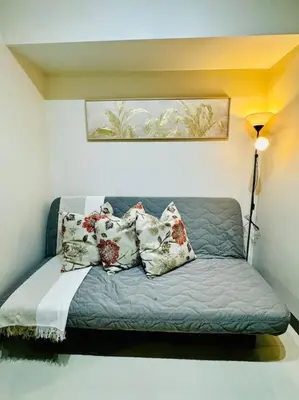a couch with pillows on it in a room at 10F Luxury 1BR at Park Mckinley West near Venice Mall in Manila