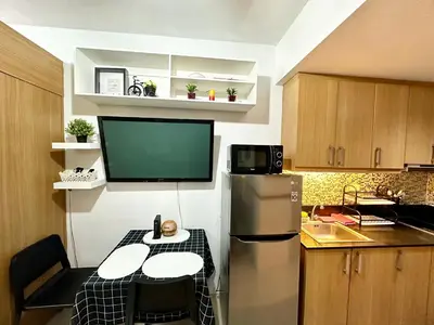 a small kitchen with a refrigerator and a table at Kathys Crib with balcony Pool view at Shell Residence in Manila