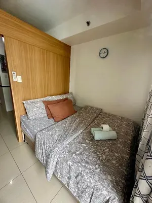a bedroom with a bed with a clock on the wall at Kathys Crib with balcony Pool view at Shell Residence in Manila