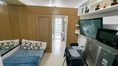 a living room with a couch and a television at Kathys Crib with balcony Pool view at Shell Residence in Manila