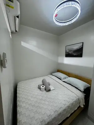 a bedroom with a bed with a chandelier above it at Bachelor Pad Shore 3 Residences in Manila