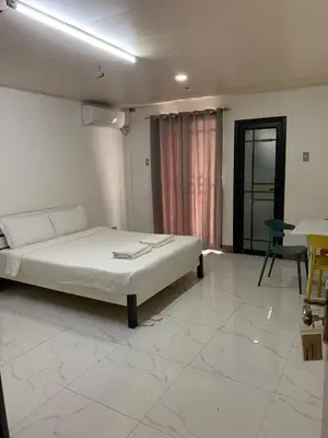 a bedroom with a bed and a table and a chair at cartimar hotel condo in Manila