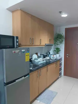 a kitchen with a stainless steel refrigerator and wooden cabinets at Shell Residences Condotel Apartment in Manila