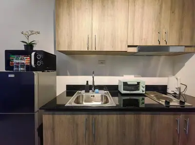 a kitchen with a sink and a microwave at 1BR Condotel with Balcony at FAME Residences #FM54 in Manila