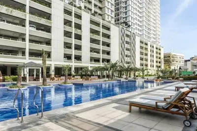 a swimming pool with chairs and a building at Excellent Location 2 BDRM Homey Wifi Near Airport in Manila