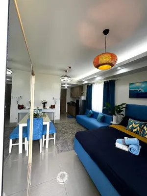 a living room with a blue bed and a kitchen at Cloud Place Shore 2 Residences in Manila