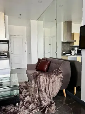 a living room with a couch with a blanket on it at Premium Suite with Balcony at The Gramercy Makati Manila in Manila