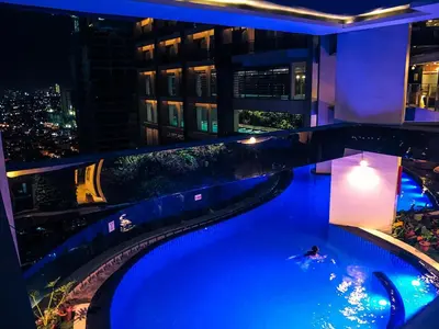 a swimming pool on top of a building at night at Premium Suite with Balcony at The Gramercy Makati Manila in Manila