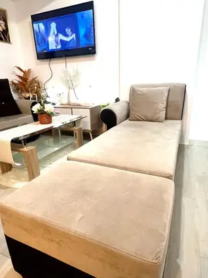 a living room with a couch and a tv on the wall at DT SUITES AND RESORTS at Azure Paranaque in Manila