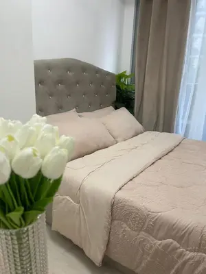 a bedroom with a bed with a vase of white flowers at DT Suites and Resorts at Azure Paranaque in Manila