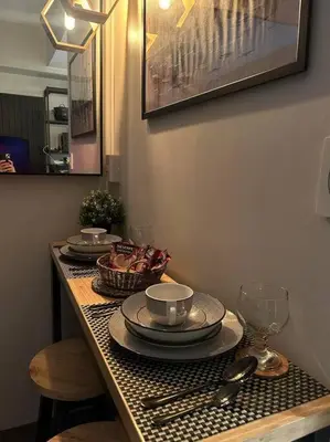 a table with plates and cups and dishes on it at BALAY MULANO at FAME RESIDENCES MANDALUYONG CITY l with balcony pool view l 200mbps wifi in Manila