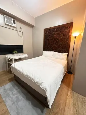 a bedroom with a white bed with a wooden headboard at S&Rs Place Space taft condominium in Manila
