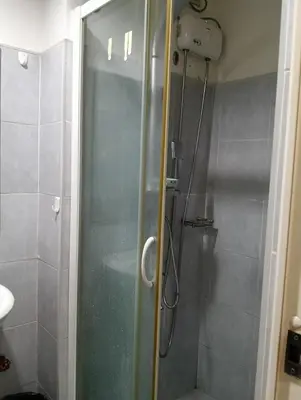 a shower with a glass door in a bathroom at Eriel condotel in Manila