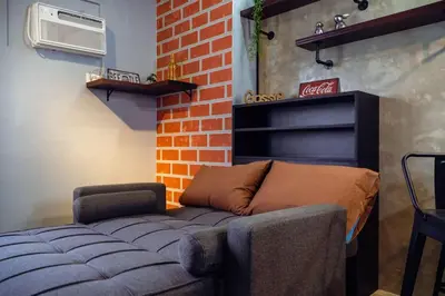 a living room with a couch and a coca cola sign at Comfy and Cozy Retreat in Manila with a Stunning View in Manila