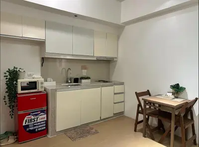 a small kitchen with a table and a refrigerator at Studio in Eastwood Fast Wifi Free Pool & Gym in Manila