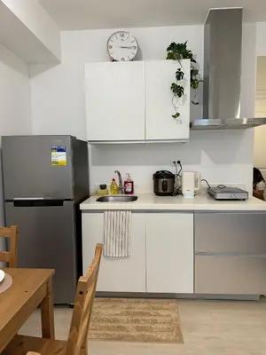 a kitchen with white cabinets and a clock on the wall at Dwell at Azure Urban Resort Residences Bahamas Tower in Manila