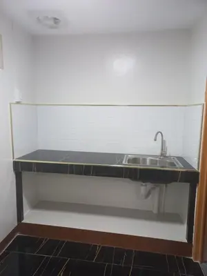 a kitchen counter with a sink in a room at Joshua Transient in Manila
