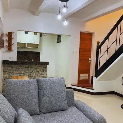 a living room with a couch and a staircase at JeSa's Serenity Sanctuary in Dasmariñas